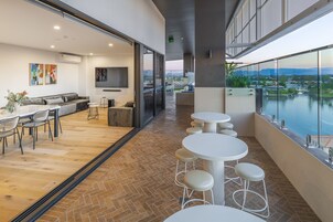 Un interior moderno con zona de comedor, un conjunto de sofás y vista a un cuerpo de agua.