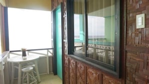 A balcony with a wooden wall, a window, and a small table with a chair. - Mila's Inn by Cocotel (Oslob)