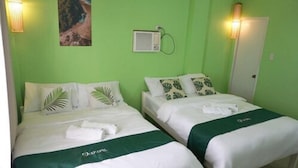 Two single beds with white linens and green bedspreads, a small air conditioning unit on the wall, and a door with a light switch. - Mila's Inn by Cocotel (Oslob)