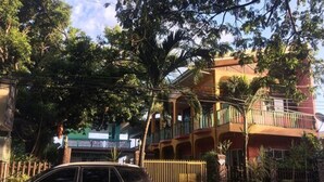 A multi-story building with balconies and a gated entrance. - Mila's Inn by Cocotel (Oslob)