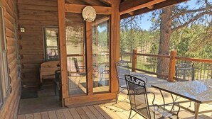 Eine Holzhütte mit einer Terrasse, einem Tisch und zwei Stühlen.