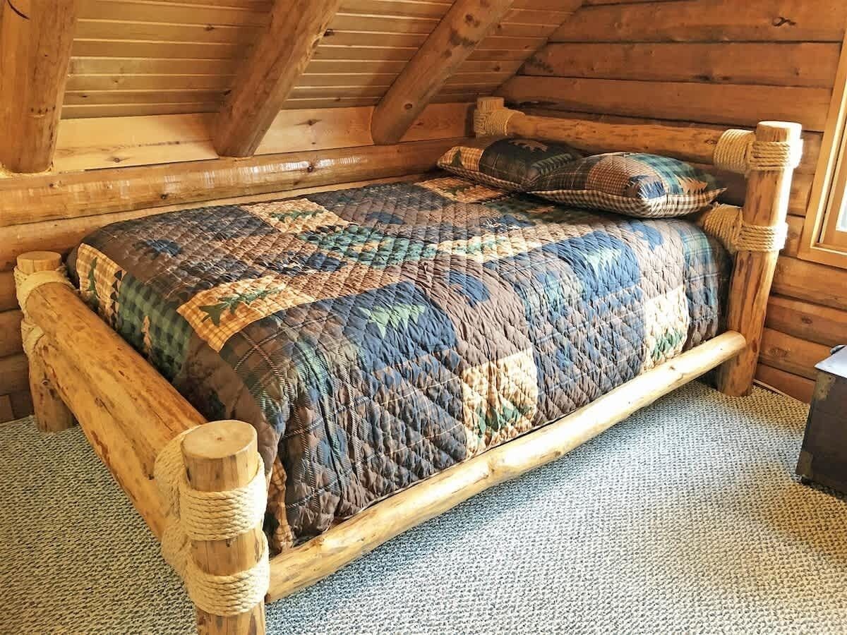 Un letto di legno con una coperta in una stanza di una baita.