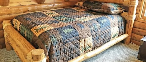 Un letto di legno con una coperta in una stanza di una baita.