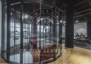 A gym with exercise equipment, a glass wall, and a logo for CA CON SERVICES. - TimurBay Seaview Stunning By CA CON (Kuantan)