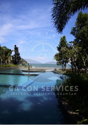 A pool area with clear blue water, surrounded by lush greenery and a view of the ocean. - TimurBay Seaview Stunning By CA CON (Kuantan)
