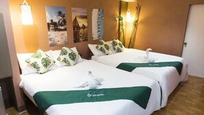 A hotel room with two beds, each with white bedding and green accents, a wall-mounted light fixture, and a door. - El Moro Beach Resort by Cocotel (Boracay Island)