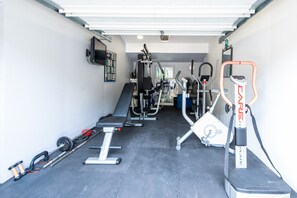 A gym with various exercise equipment including a bench, weight bench, and cardio machines.