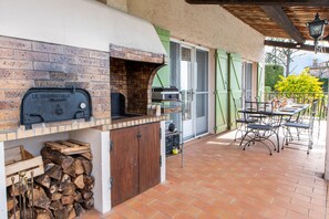 An outdoor kitchen with a brick oven, a grill, and a table with chairs.