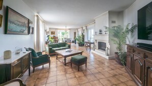 Un salón espacioso con chimenea, muebles tapizados en verde y un televisor grande.
