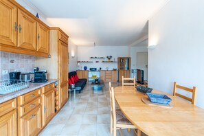 Een moderne keuken met houten kastjes, een eettafel en een zithoek met een bank.
