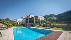 Una propiedad residencial con piscina, un muelle de madera y un muro de piedra.