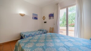 A bedroom with two beds, a window with curtains, and wall art.