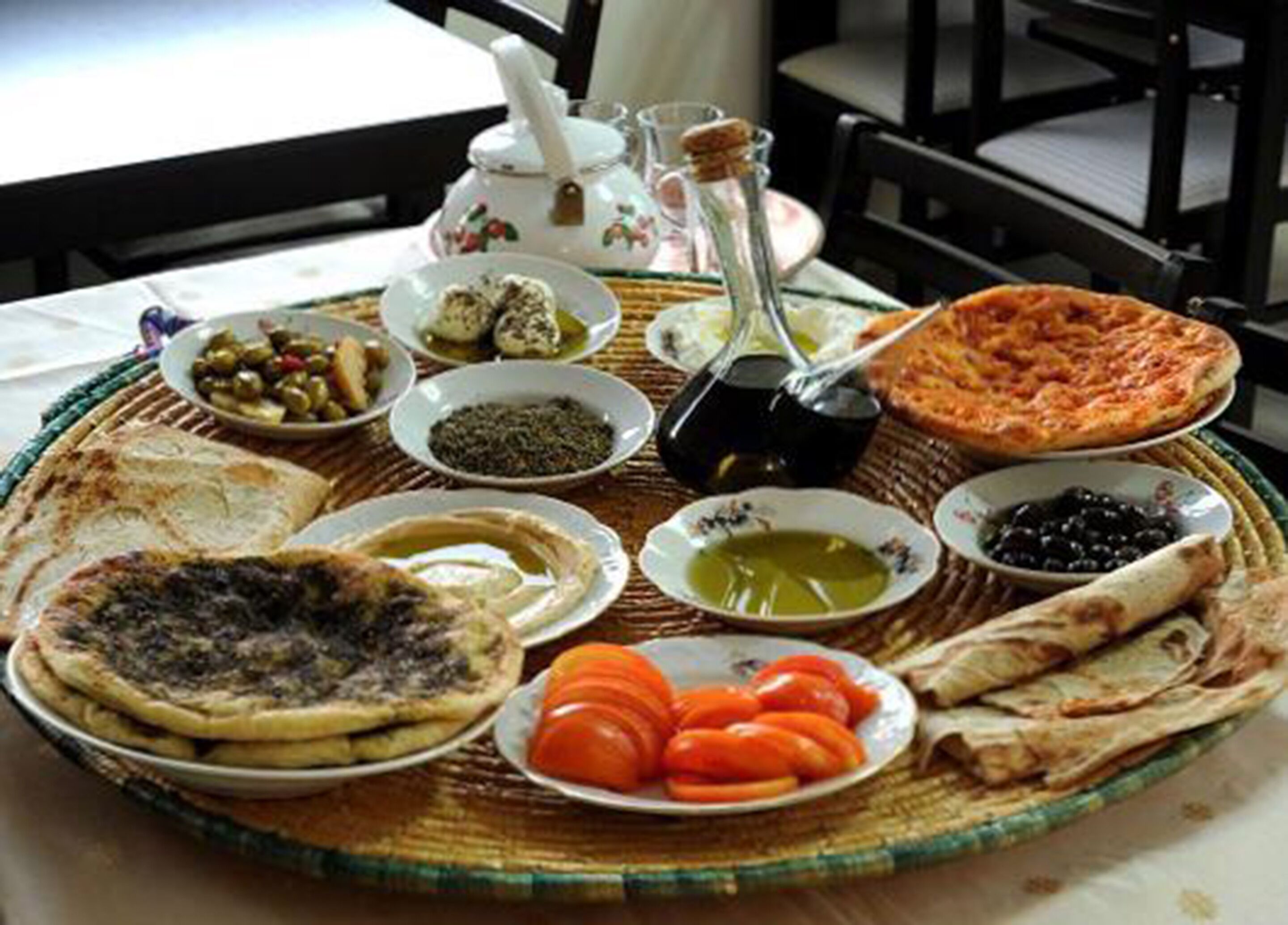 Une table garnie de divers plats, notamment des galettes, des olives, des tomates et une pizza.