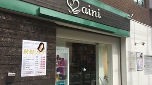 A storefront with a green awning and a sign that reads "aini".