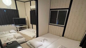 A hotel room with a large bed, a smaller bed, a desk with a chair, a television, and a window.