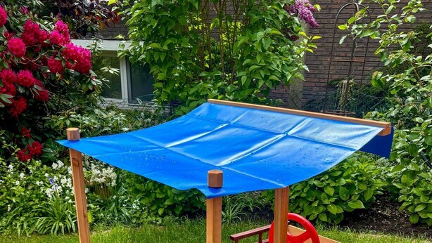 A wooden play structure with a blue roof and a lifebuoy decoration.