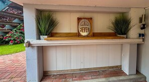 A wooden bench with a sign that reads 'Friesisches Brauhaus' and two potted plants on either side.