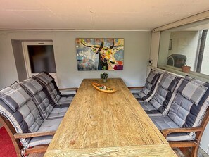 Un comedor con mesa de madera, bancos acolchados, un cuadro en la pared y una ventana con vistas.