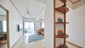 Un salon moderne avec un canapé, une table basse et une étagère en bois ornée d’objets décoratifs.