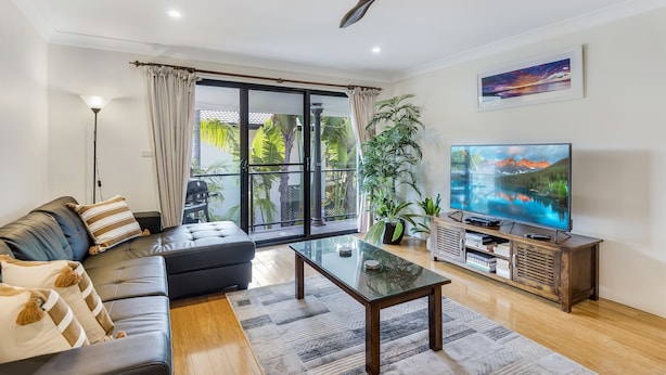 A modern living room with a sofa, coffee table, TV, and a ceiling fan.