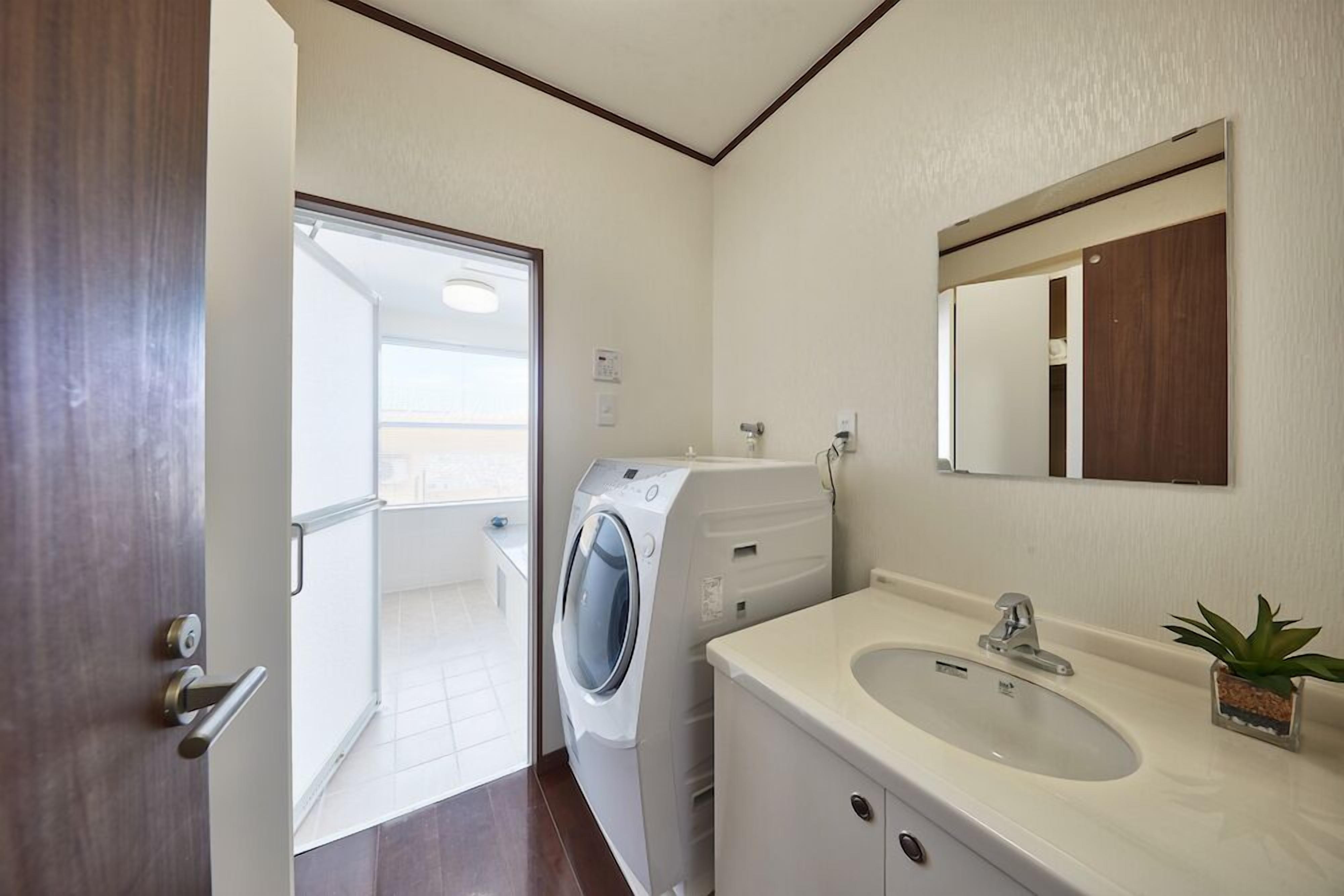 A modern bathroom with a built-in washing machine, a sink, and a mirror.