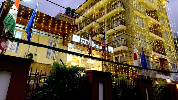 A multi-story hotel with balconies, string lights, and flags. - Himalayan Suite Hotel (Kathmandu)