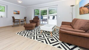 A modern living room with a brown sofa, a white coffee table, and a patterned rug. - Vacation apartment 14 - Haus Seeperle (Esens)