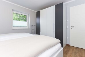 Ein Schlafzimmer mit Bett, Kleiderschrank, Fenster und Tür.