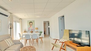 Ein modernes Wohnzimmer mit Sofa, Fernseher und Essbereich.