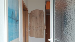 A hallway with a wooden wall decoration, a framed painting, and a door leading to another room. - Beautiful bungalow near the Baltic Sea, family-friendly and quiet (Nienhagen)
