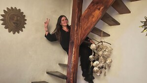 Eine Treppe mit Holzstufen und Geländer, eine dekorative Sonne an der Wand und ein roter Sessel mit einer Zeitschrift darauf.