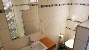 A bathroom with a sink, mirror, toilet, and a trash bin. - Hof Hahnenberg (Wagenfeld)