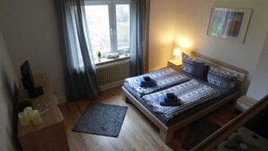 Ein Schlafzimmer mit Bett, Fenster, Heizkörper, Nachttisch und Lampe.