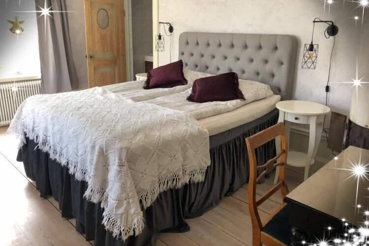 A bedroom with a bed, bedside tables, a chair, and a small table.