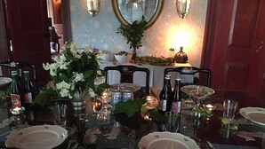 Une table à manger dressée avec des assiettes, des verres et des bouteilles, entourée de chaises.