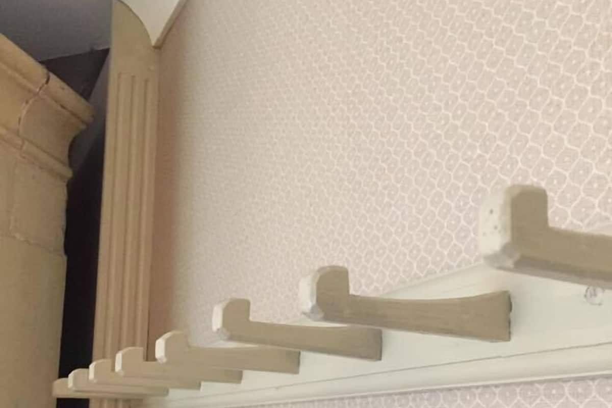 A wall with a decorative wooden shelf and a patterned wallpaper.