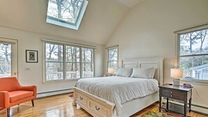 Un dormitorio con una cama grande, una mesita de noche, una silla y un tragaluz.