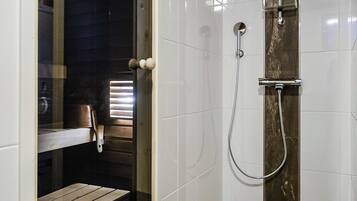 Un angolo doccia con porta in vetro, una panca e pareti rivestite di piastrelle.