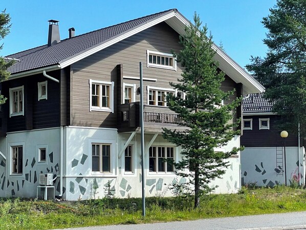 A two-story residential building with a sloped roof, multiple windows, and a balcony.