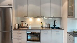 Una cocina moderna con electrodomésticos de acero inoxidable, horno integrado y un lavamanos.