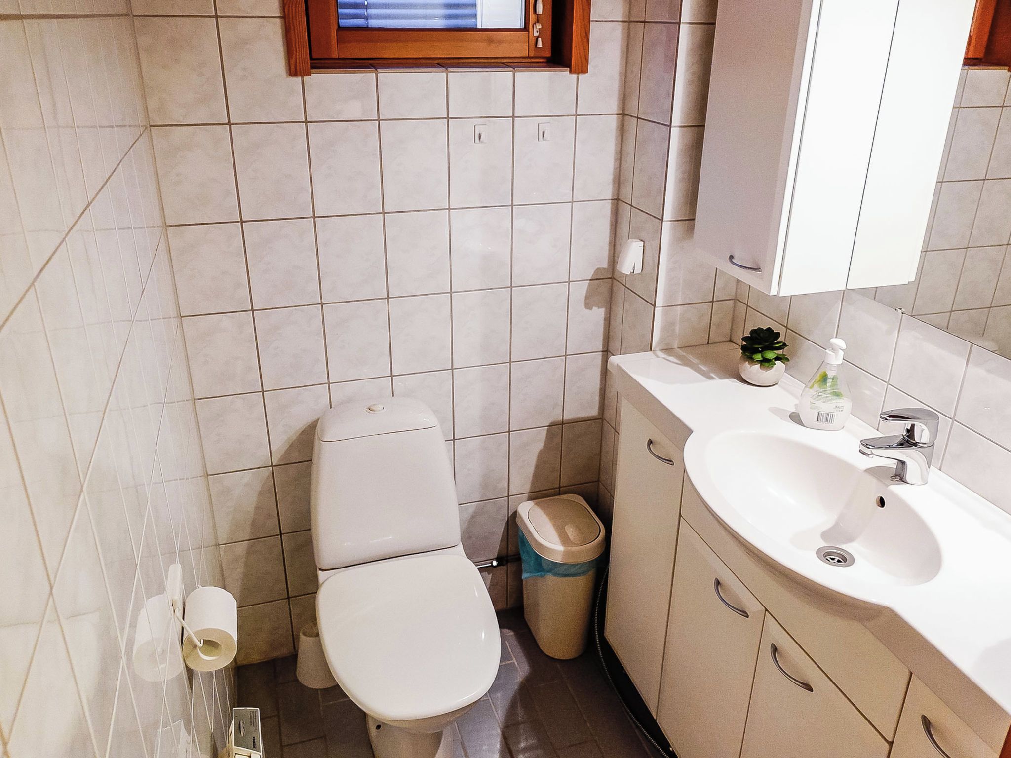 Ein Badezimmer mit Toilette, Waschbecken, Mülleimer und Spiegel.