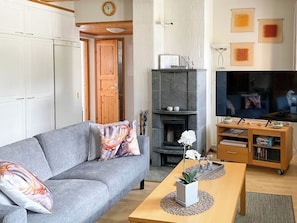 A living room with a grey sofa, a wooden coffee table, a fireplace, and a television. - Levin rinnelinna a8 by Interhome (Kittilä)