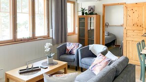 Una sala acogedora con un sofá gris, una mesa de centro de madera y un aparador con puertas de cristal.