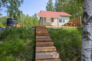 A wooden staircase leading to a small cabin with a red roof, surrounded by greenery. - Peace and Privacy Travel - Aulanko Lake Hide-out (Hameenlinna)