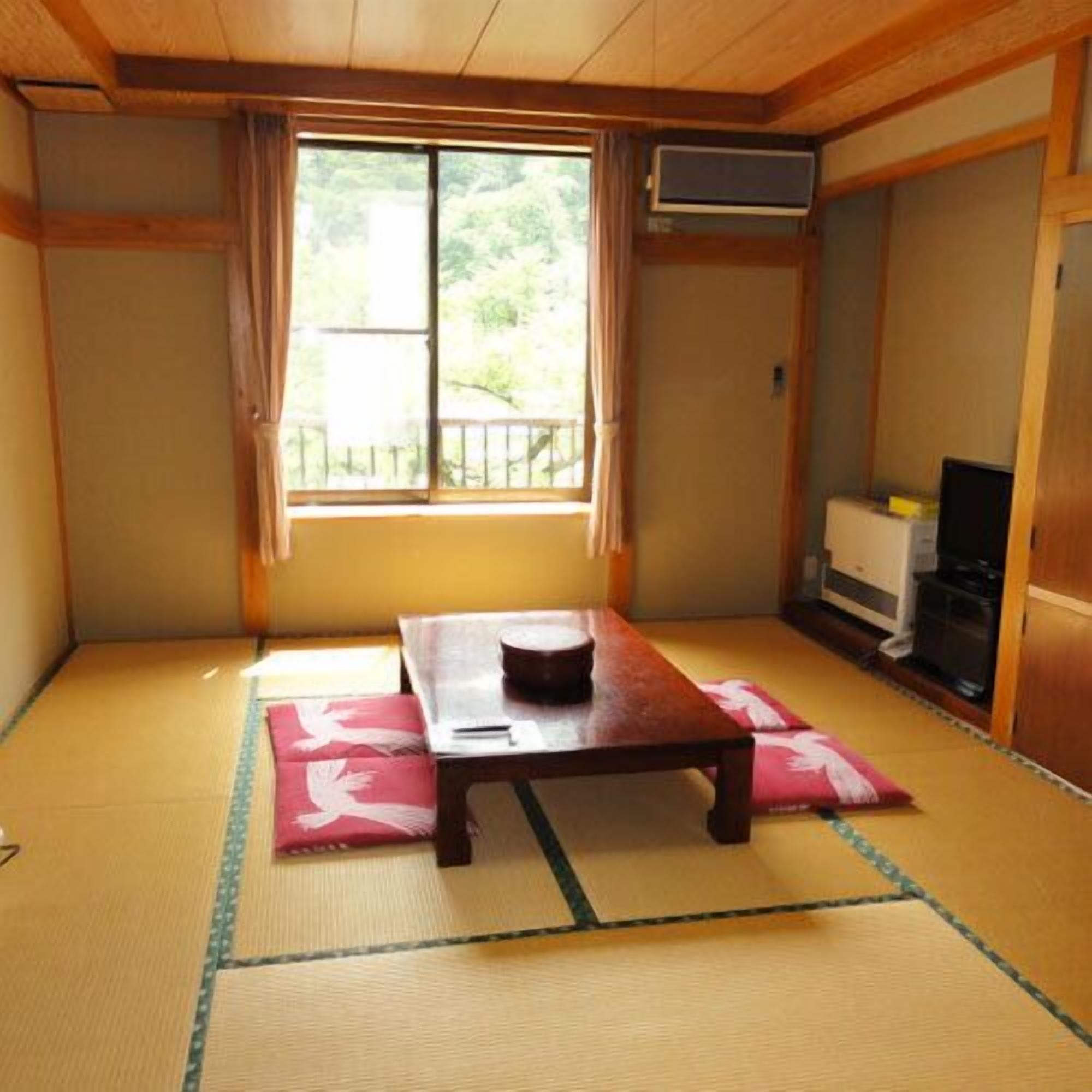 A traditional Japanese room with tatami flooring, a low wooden table, and a sliding door.