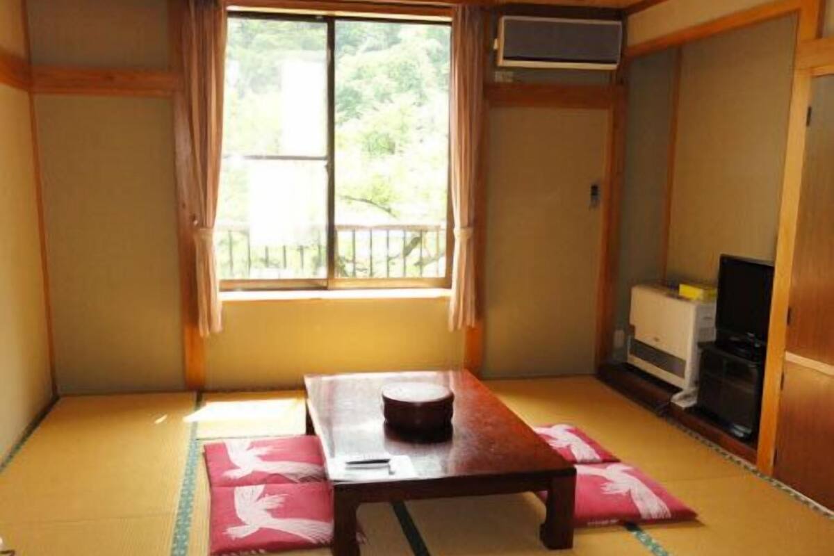Um quarto japonês tradicional com tatames, uma mesa de madeira baixa e uma porta deslizante.