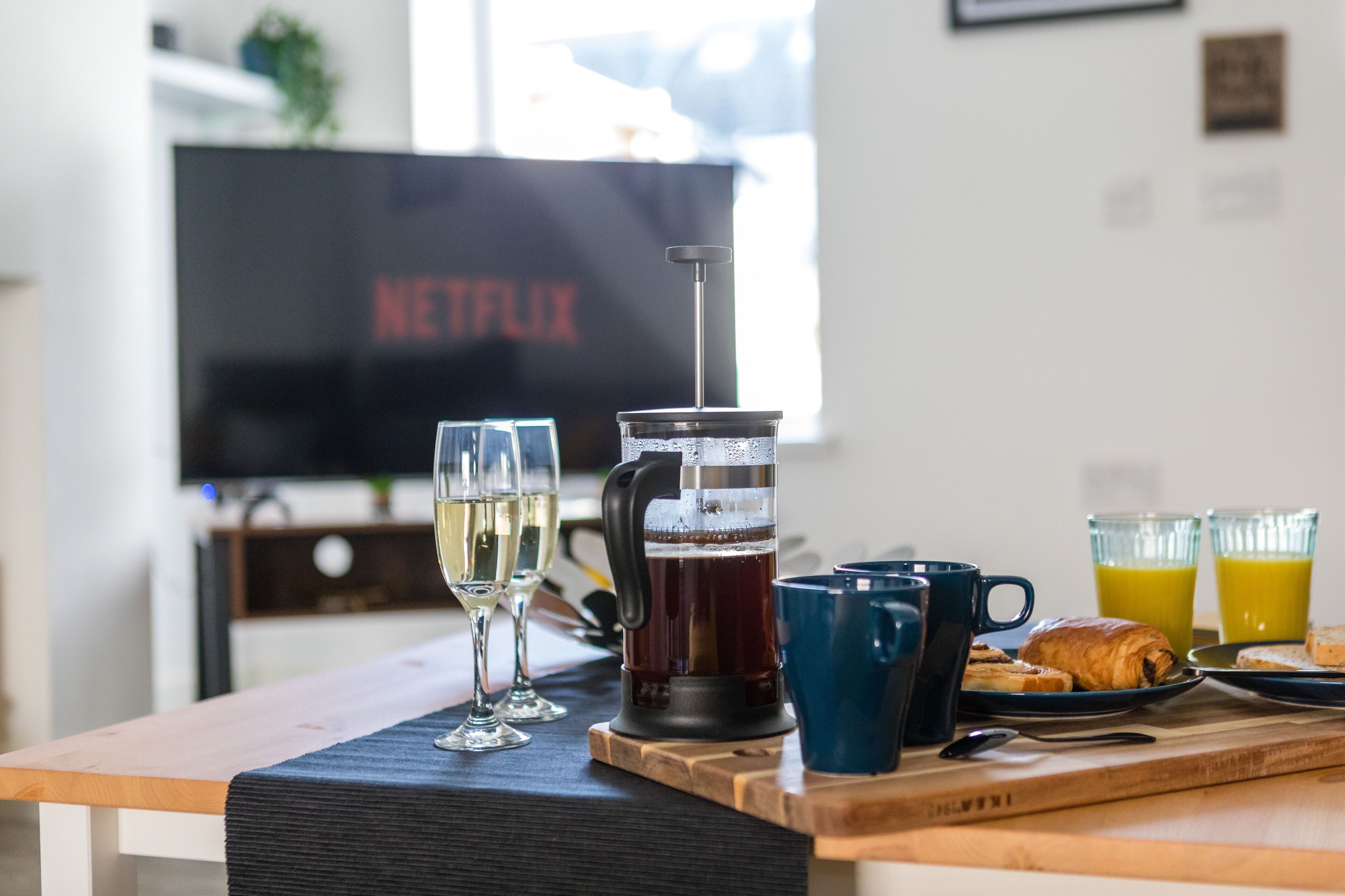 A breakfast table with a coffee press, glasses of white wine, and juice.