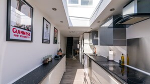 A modern kitchen with a skylight, stainless steel appliances, and a black countertop. - The Hollywood Beautiful 3 Bedroom House (Cardiff)