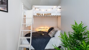 A bunk bed with a ladder, a wall-mounted shelf, and a string of lights. - The Hollywood Beautiful 3 Bedroom House (Cardiff)