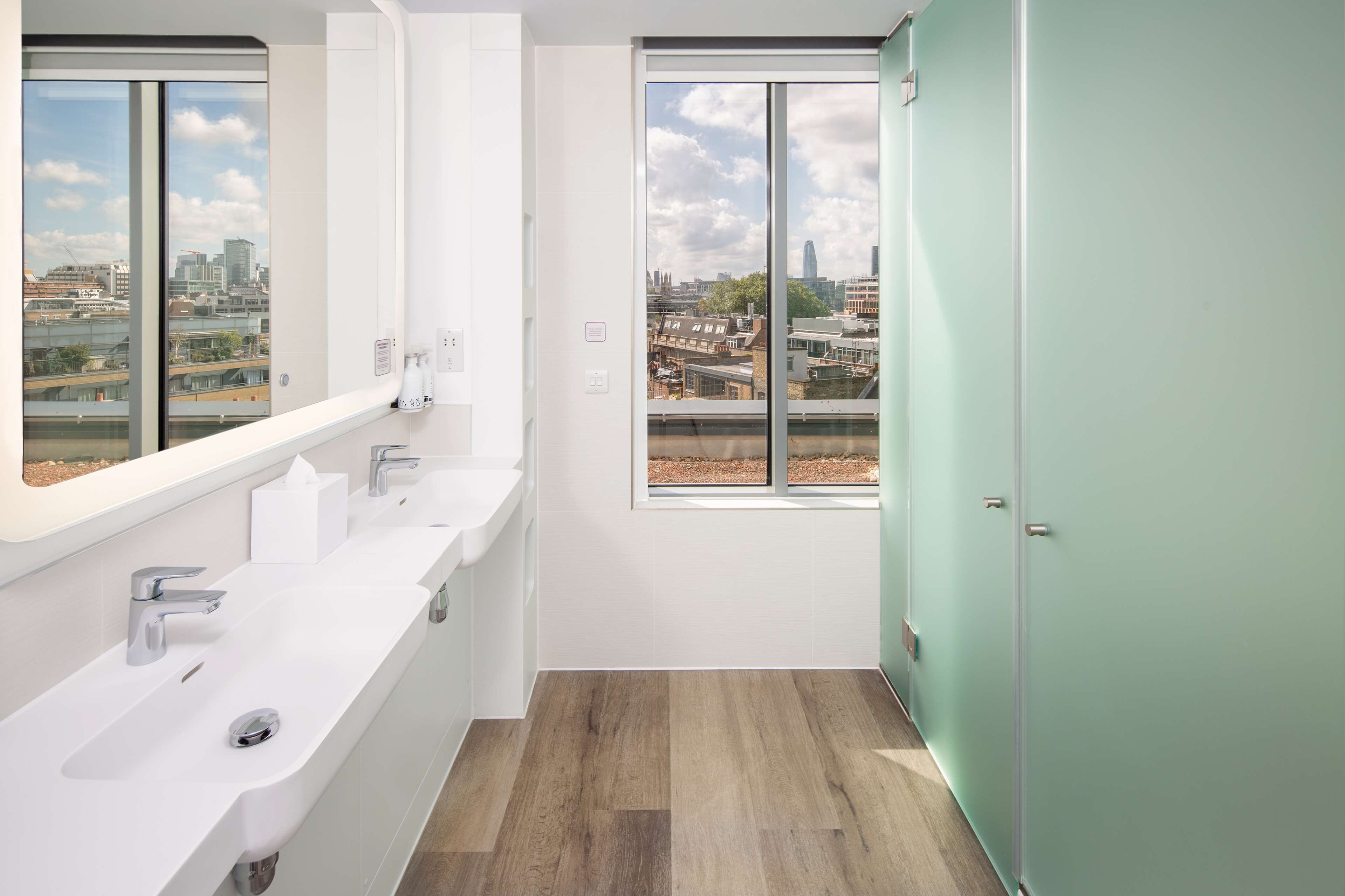Un baño moderno con un ventanal grande, un lavabo y un espejo.